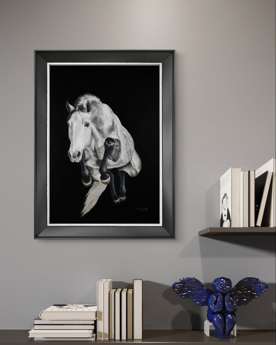 Framed black and white horse portrait on a wall with books and decorative items below.