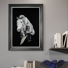 Framed black and white horse portrait on a wall with books and decorative items below.