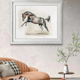 Framed artwork of a horse on a wall above a sofa in a living room.