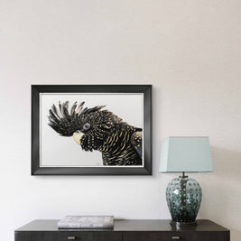 Framed artwork of a bird on a wall above a dark wooden console table with a lamp.