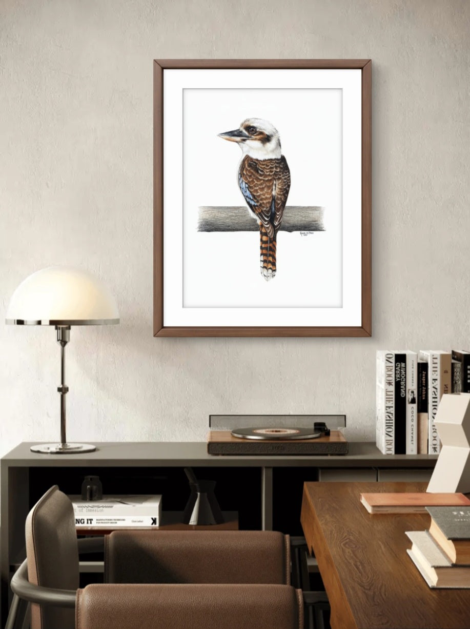 Framed artwork of a bird on a branch in a room with a desk and lamp.