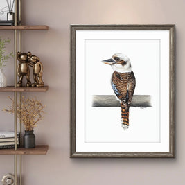 Framed artwork of a bird on a branch in a room with a shelf and decor.