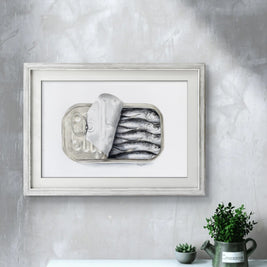 Framed artwork of a still life with fish on a gray wall above a white cabinet.