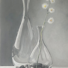 Two clear glass vases with pebbles and a single white flower on a gray background