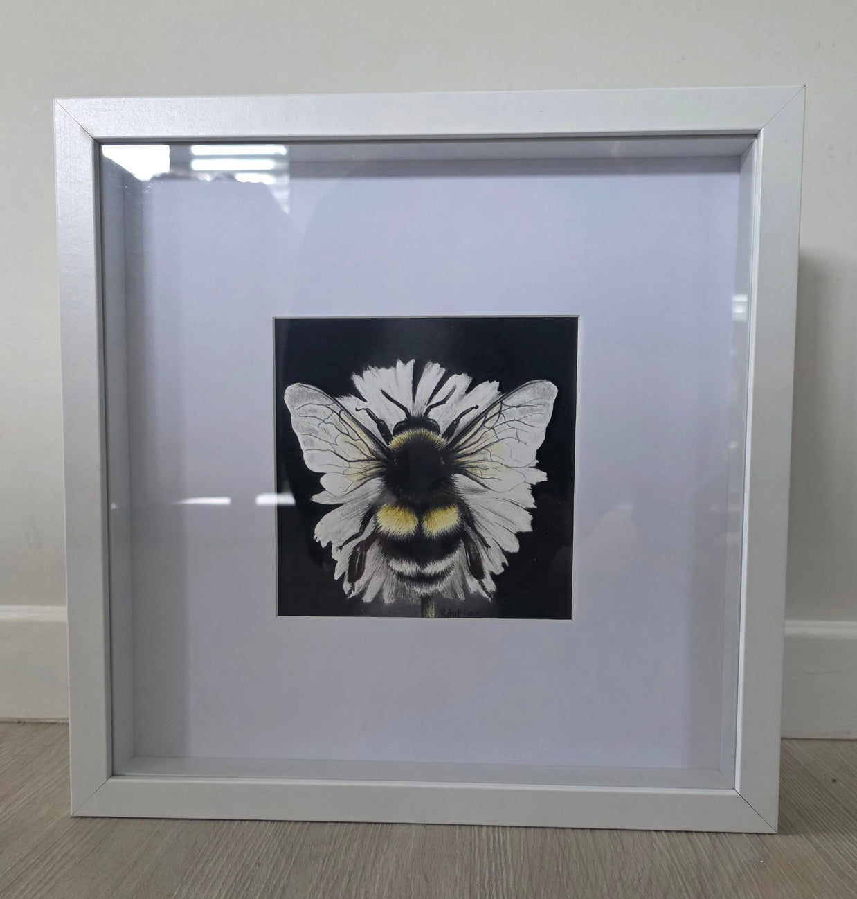 Framed artwork of a bee with white wings on a black background