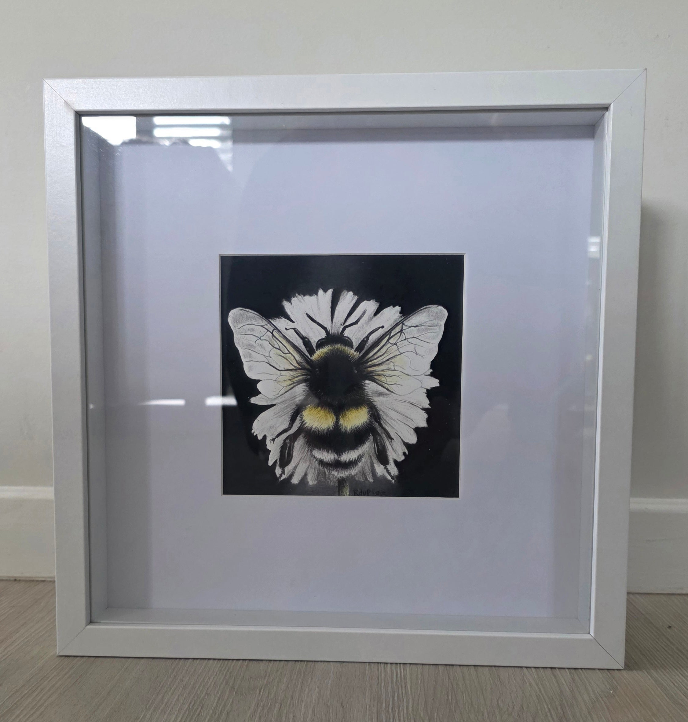 Framed artwork of a bee with white wings on a black background