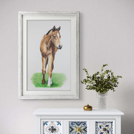 Framed painting of a horse on a wall above a decorative cabinet with a vase of flowers.