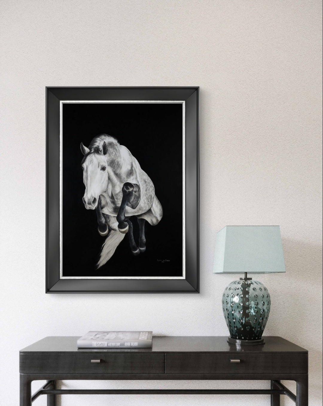Framed black and white artwork of a horse head on a wall above a console table with a lamp.