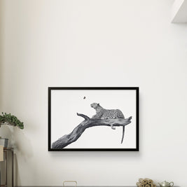 A framed black and white art print of a leopard resting on a branch, displayed on a white wall in a modern living room setting.