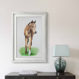 Framed picture of a horse on a wall above a table with a lamp.