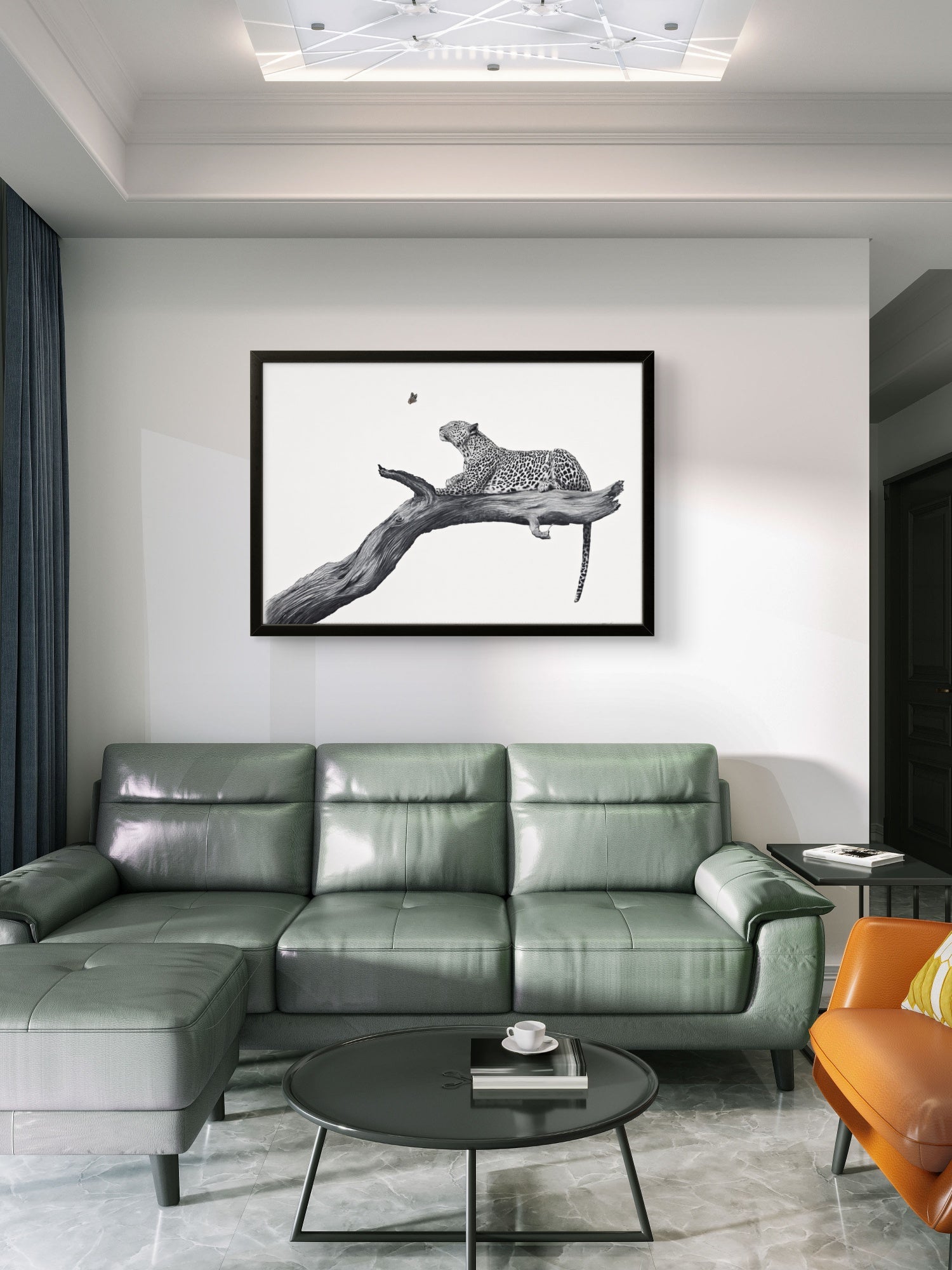 A framed black and white art print of a leopard on a branch, displayed on a white wall above a green leather sectional sofa in a modern living room setting.