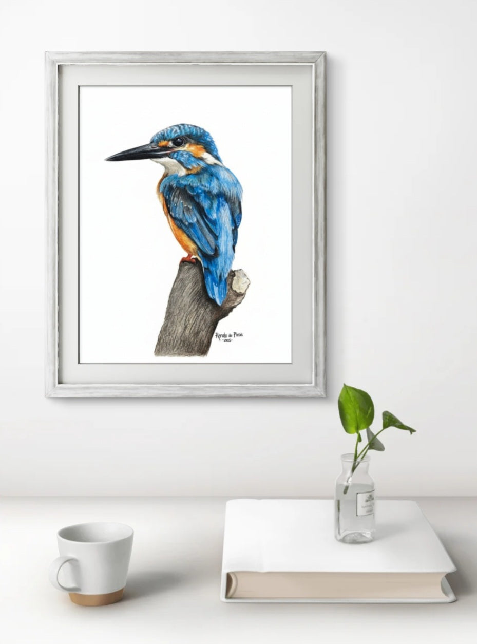 Framed artwork of a blue bird on a branch with a white mug and book on a table.