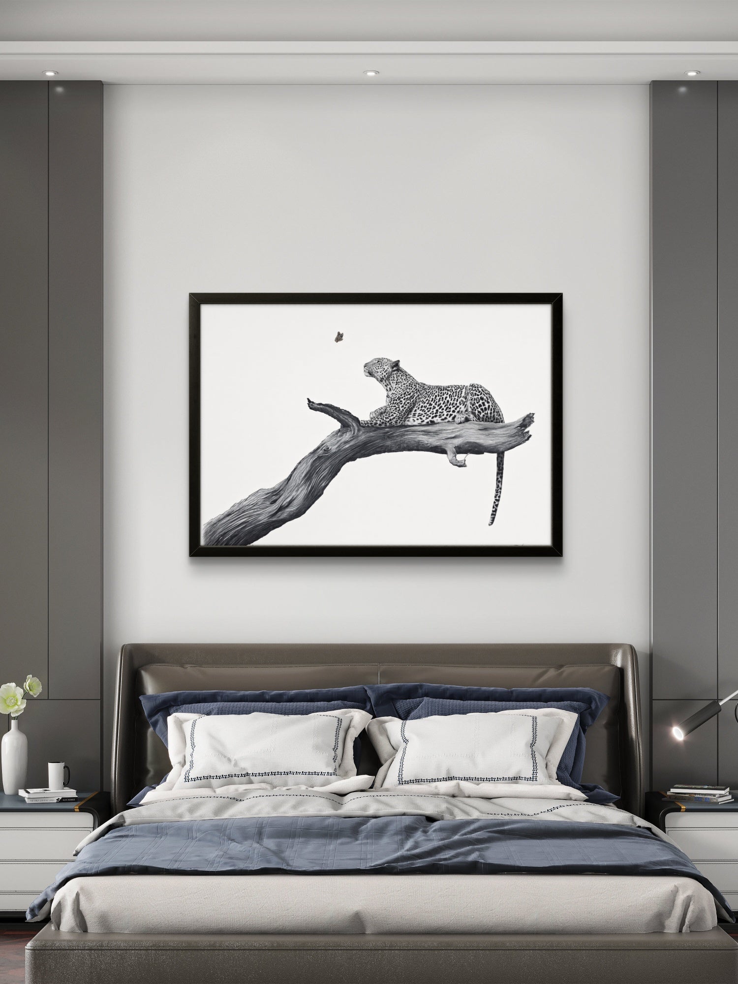 A framed black and white art print of a leopard resting on a branch, displayed on a light gray wall above a modern bed in a bedroom setting.
